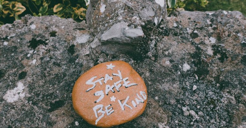 Empathy - Stay Safe Be Kind text carved on stone in green park during coronavirus pandemic