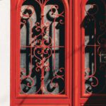 Entry Strategies - A red door with ornate ironwork on the side