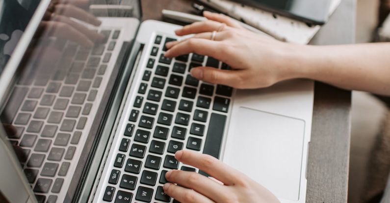 Employee Turnover - From above of unrecognizable woman sitting at table and typing on keyboard of computer during remote work in modern workspace